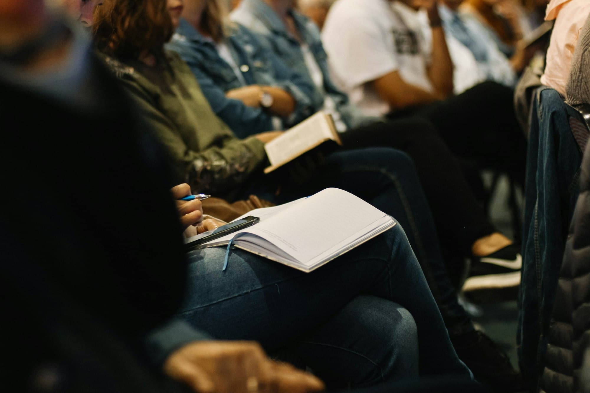 People seated at a meeting taking notes — a strata committee gathering to discuss building decisions
