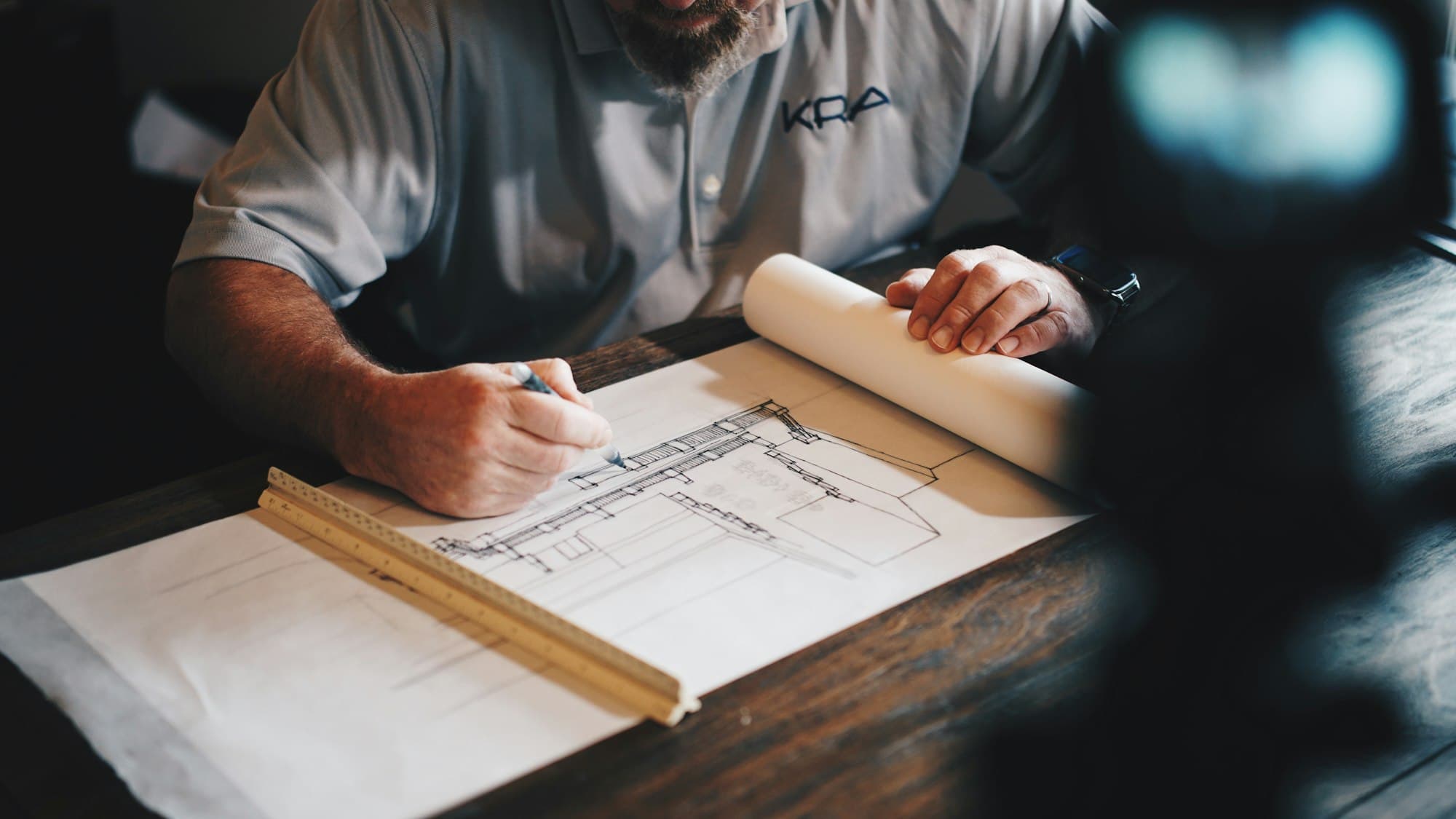 An architect reviewing building plans spread across a desk