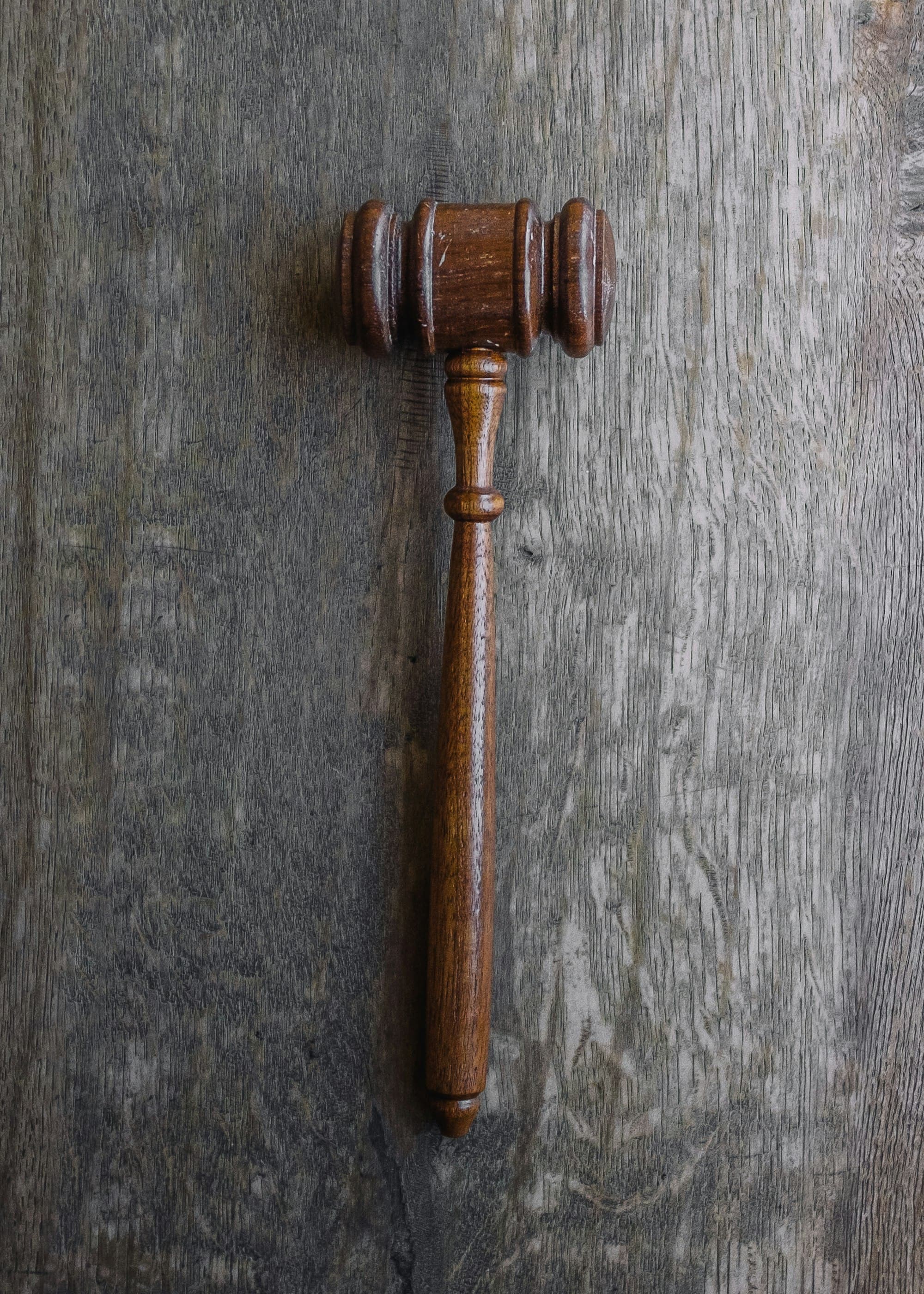 A brown wooden gavel resting on a grey wooden surface